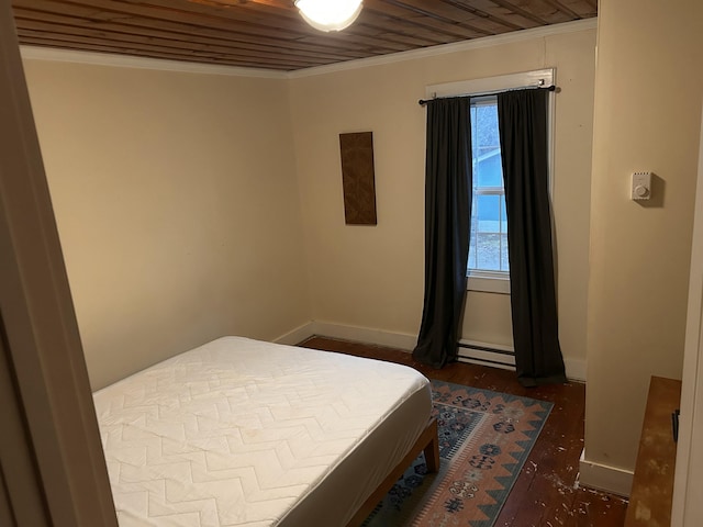 bedroom featuring a baseboard heating unit, ornamental molding, wood finished floors, and baseboards