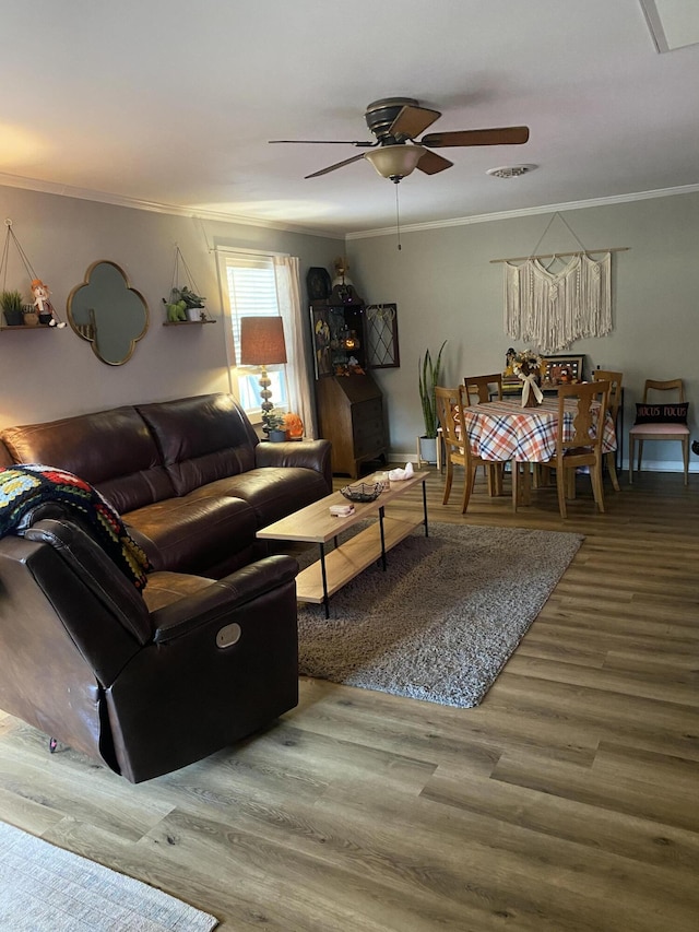 living room with ornamental molding, a ceiling fan, visible vents, and wood finished floors