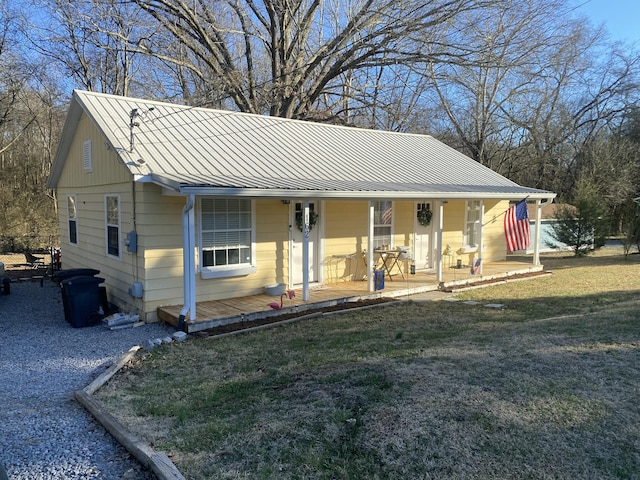 bungalow featuring covered porch, metal roof, and a front yard