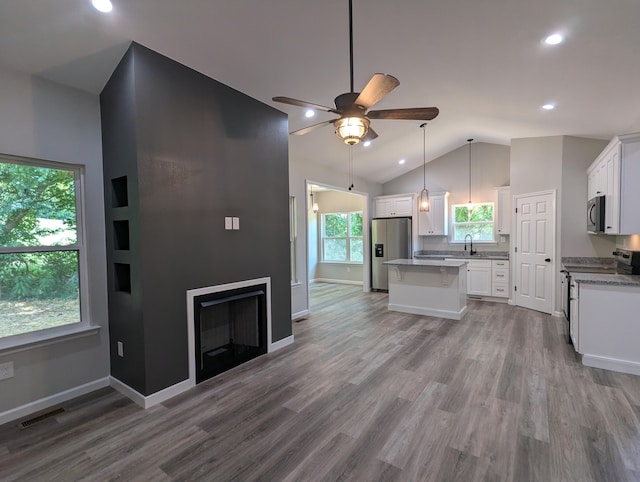 kitchen featuring decorative light fixtures, vaulted ceiling, stainless steel appliances, and white cabinetry