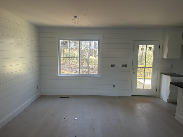 1775 Lenox Dr NW, Cleveland, TN 37312 - unfurnished dining area with wood walls, a healthy amount of sunlight, light wood-type flooring, and visible vents