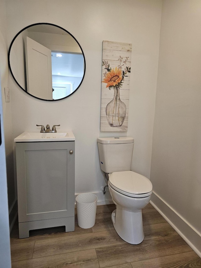 bathroom with hardwood / wood-style floors, vanity, and toilet