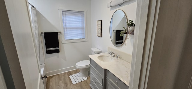 bathroom with hardwood / wood-style floors, vanity, toilet, and a shower