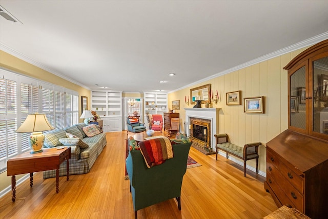 living room featuring ornamental molding, built in features, and light hardwood / wood-style flooring