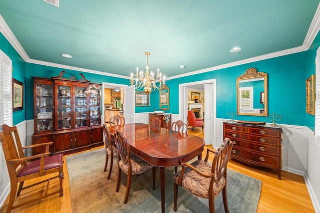 dining room with crown molding, light hardwood / wood-style floors, and a notable chandelier