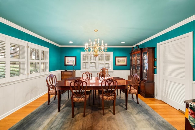 dining room with ornamental molding, hardwood / wood-style floors, and a notable chandelier