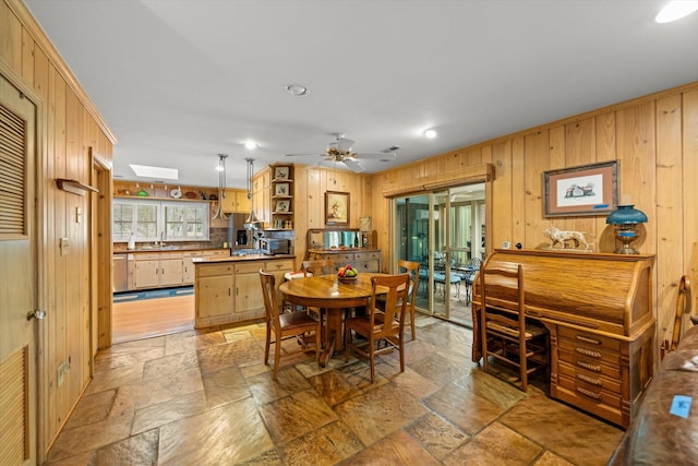 dining room with ceiling fan, wooden walls, and sink