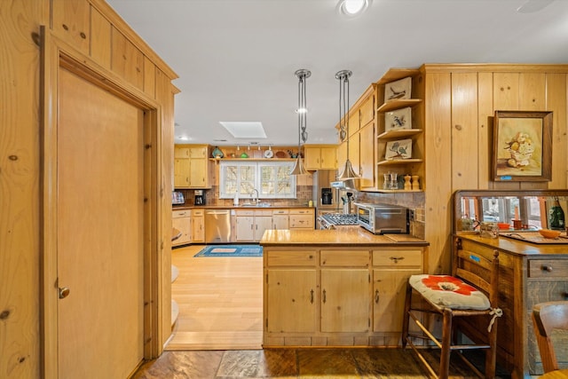 kitchen featuring pendant lighting, sink, a skylight, decorative backsplash, and stainless steel dishwasher