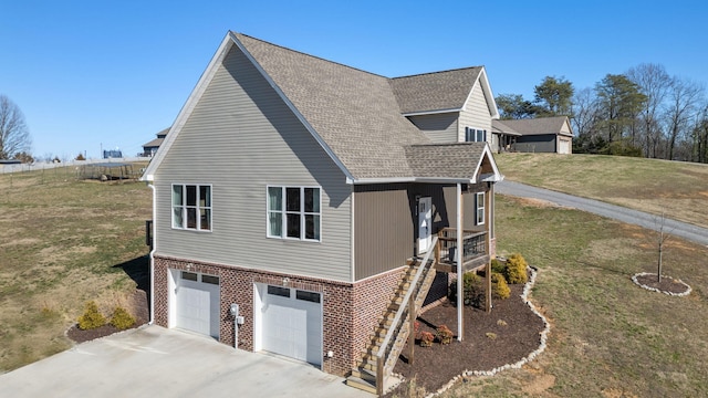 view of side of home with brick siding, a yard, a shingled roof, concrete driveway, and an attached garage