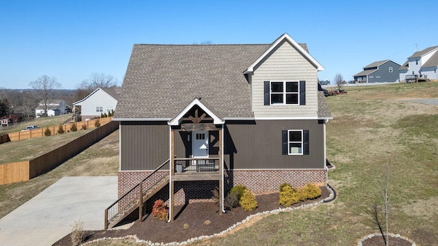 view of front facade featuring a shingled roof, a front yard, and fence