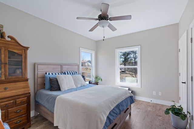 bedroom with wood finished floors, a ceiling fan, and baseboards