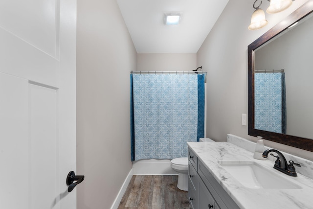 bathroom with toilet, wood finished floors, vanity, and baseboards