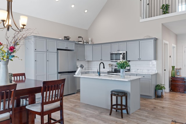 kitchen featuring stainless steel appliances, gray cabinets, a sink, and light wood finished floors