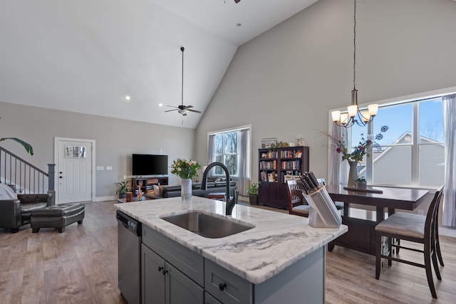 kitchen featuring dishwasher, light wood finished floors, ceiling fan with notable chandelier, and a sink