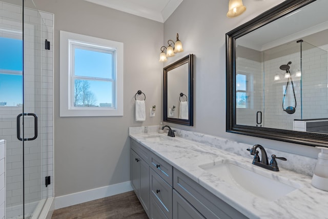 bathroom with crown molding, a shower stall, a sink, and baseboards