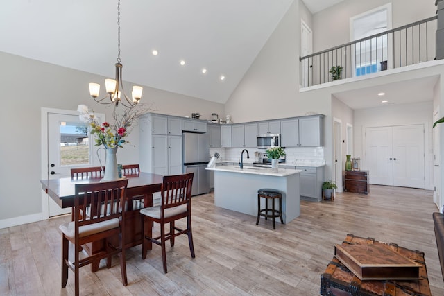 dining room featuring baseboards, light wood finished floors, a high ceiling, and a notable chandelier