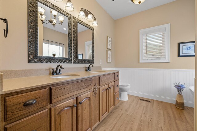 bathroom with hardwood / wood-style flooring, vanity, toilet, and an inviting chandelier