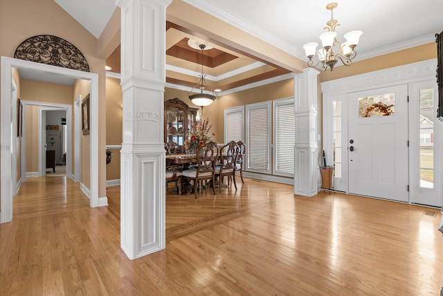 foyer entrance featuring a notable chandelier, decorative columns, crown molding, and light hardwood / wood-style flooring