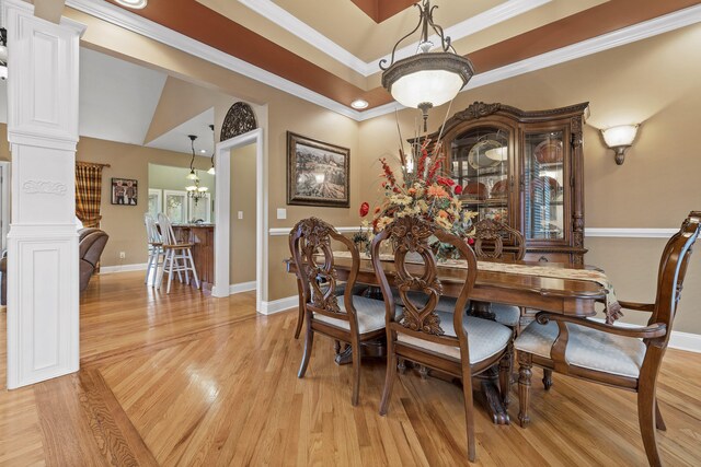 dining area featuring light wood-type flooring, decorative columns, ornamental molding, a chandelier, and lofted ceiling