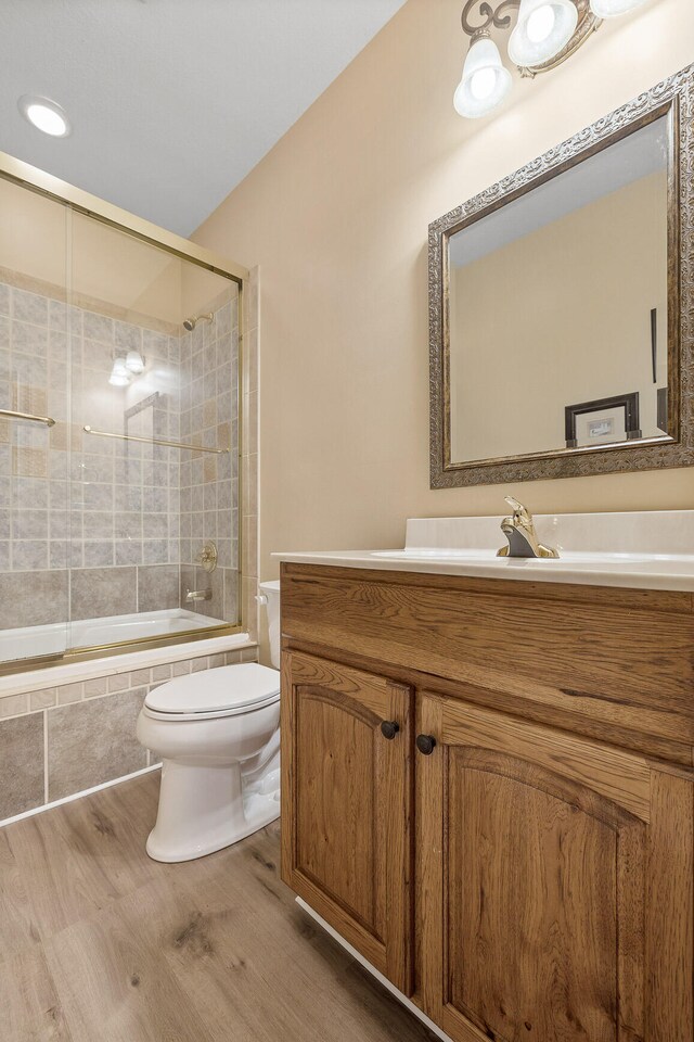 full bathroom with vanity, hardwood / wood-style flooring, toilet, and enclosed tub / shower combo