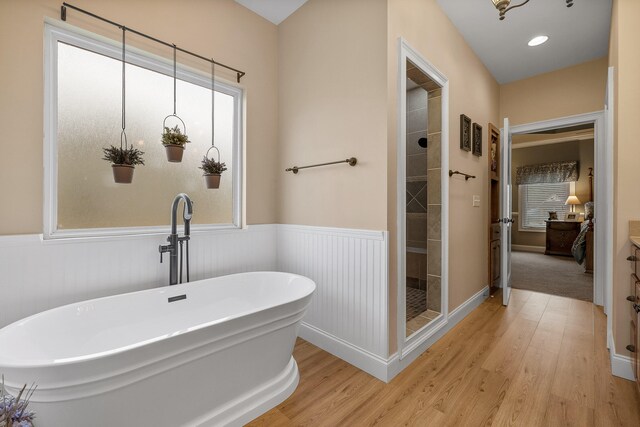 bathroom with hardwood / wood-style floors, vanity, and shower with separate bathtub