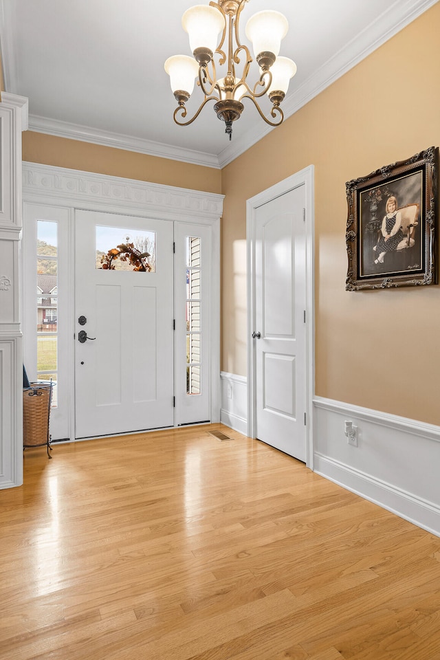 entrance foyer featuring an inviting chandelier, crown molding, and light hardwood / wood-style flooring