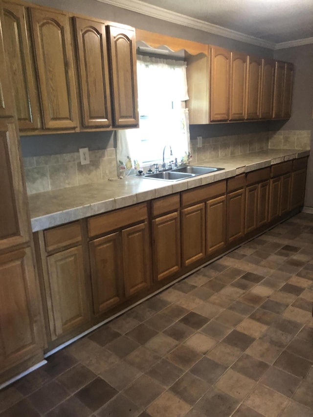 kitchen featuring tasteful backsplash, a sink, tile counters, and crown molding