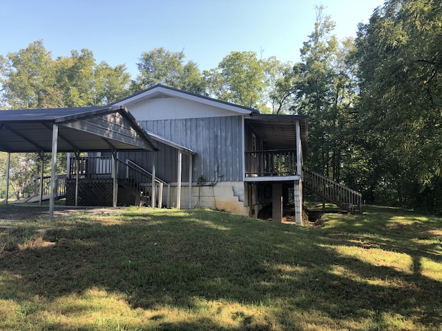 rear view of house featuring a lawn and stairs