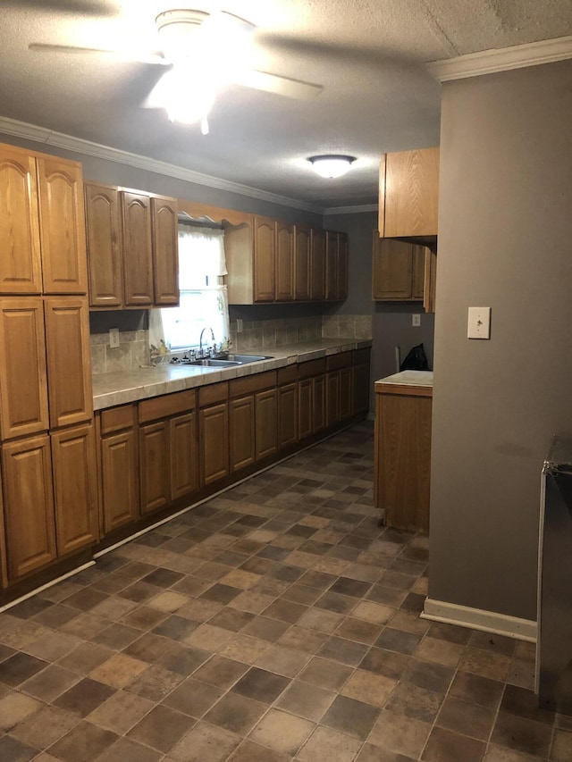 kitchen with crown molding, tasteful backsplash, brown cabinetry, a sink, and ceiling fan