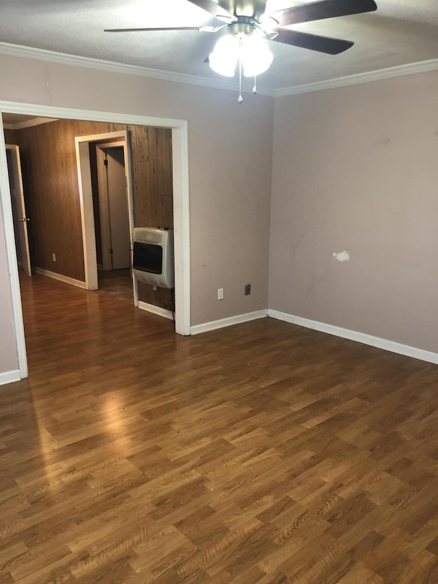 unfurnished room with dark wood-style flooring, crown molding, heating unit, ceiling fan, and baseboards