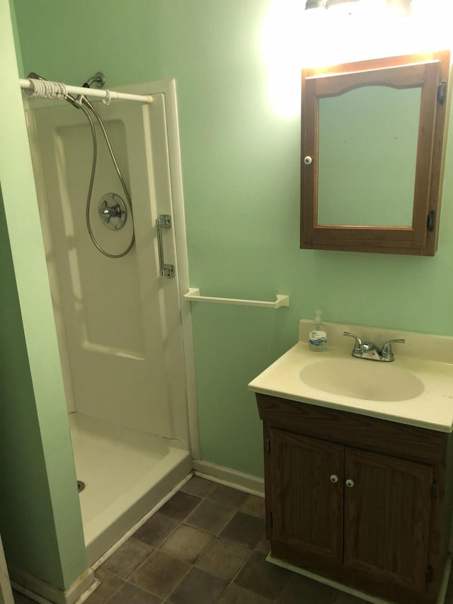 bathroom with a shower stall, baseboards, and vanity