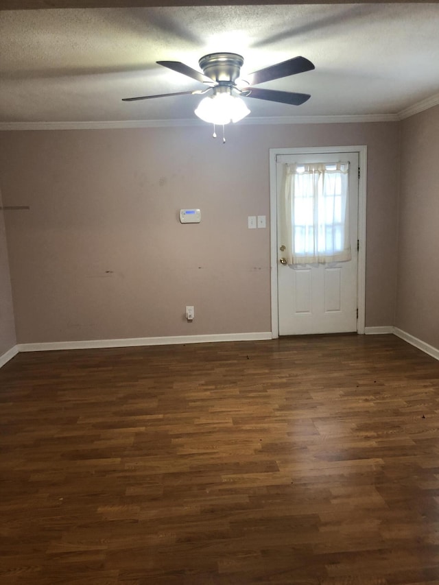 interior space featuring a textured ceiling, ornamental molding, dark wood finished floors, and baseboards