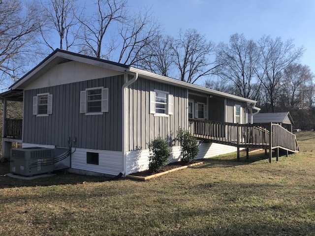 view of side of property featuring board and batten siding, central AC, a lawn, and a deck