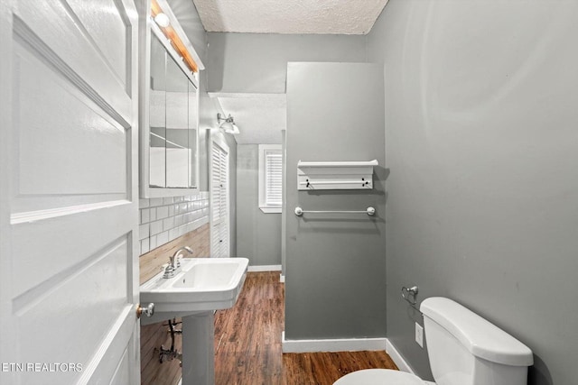 bathroom with a textured ceiling, wood-type flooring, and toilet