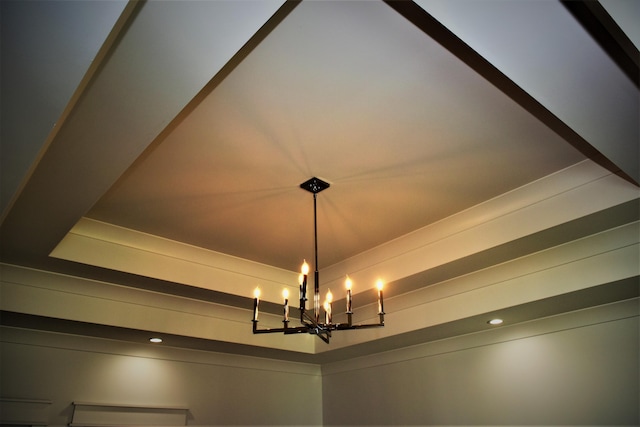 interior details featuring a raised ceiling and a notable chandelier