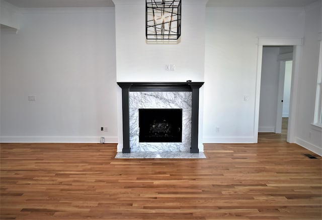 unfurnished living room featuring crown molding, a fireplace, visible vents, wood finished floors, and baseboards