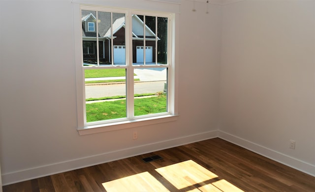 unfurnished room featuring dark wood-type flooring, visible vents, and baseboards