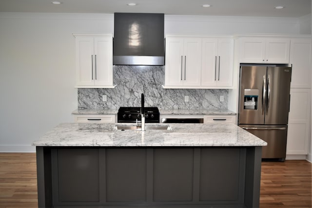 kitchen with decorative backsplash, stainless steel fridge with ice dispenser, wall chimney exhaust hood, white cabinetry, and a sink