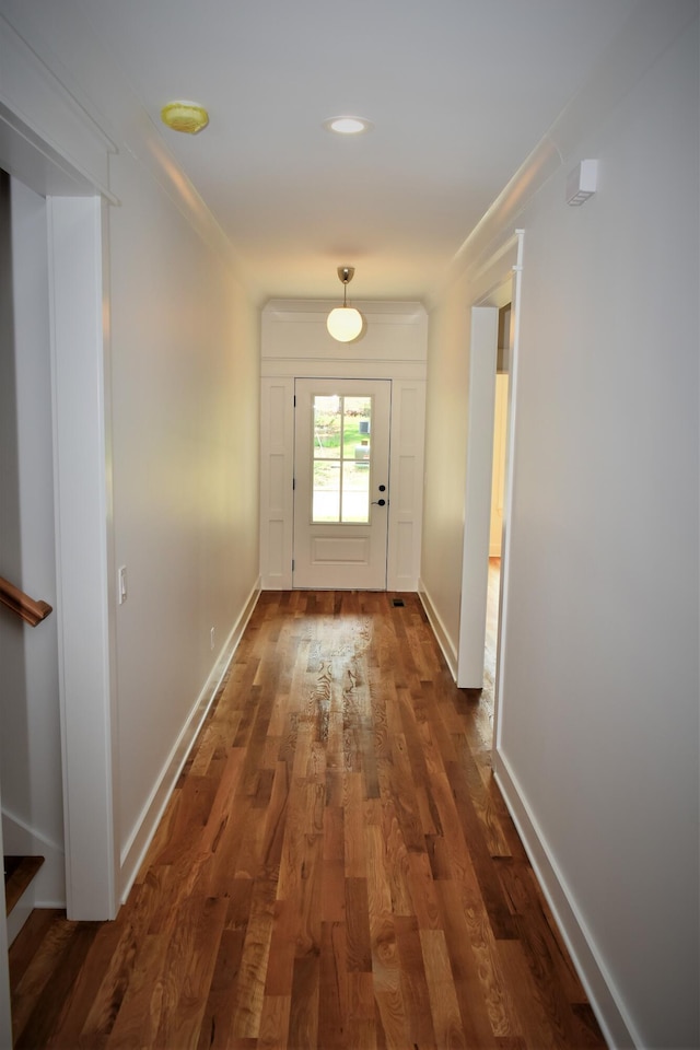 doorway to outside with crown molding, wood finished floors, and baseboards