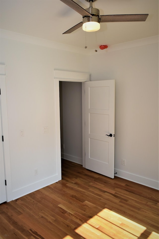 unfurnished bedroom with a ceiling fan, baseboards, crown molding, and wood finished floors