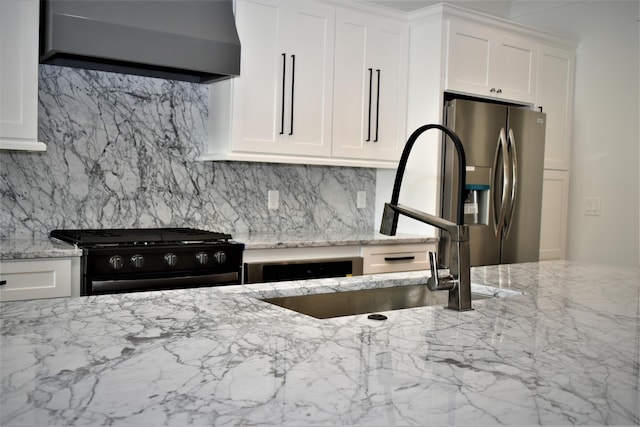 kitchen with decorative backsplash, stainless steel fridge, black range with gas cooktop, and wall chimney exhaust hood