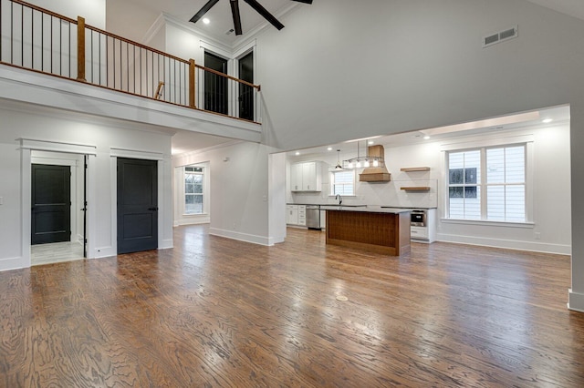 unfurnished living room featuring dark hardwood / wood-style floors, high vaulted ceiling, ceiling fan, and crown molding