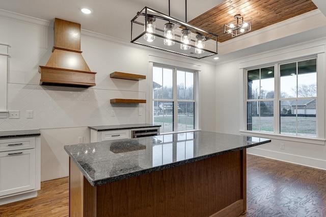 kitchen featuring white cabinets, custom range hood, tasteful backsplash, and hanging light fixtures