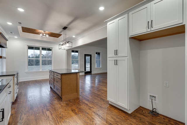 kitchen featuring dark hardwood / wood-style floors, crown molding, dark stone counters, decorative light fixtures, and white cabinets