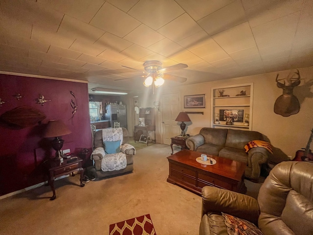 living room with built in shelves, ceiling fan, and carpet floors