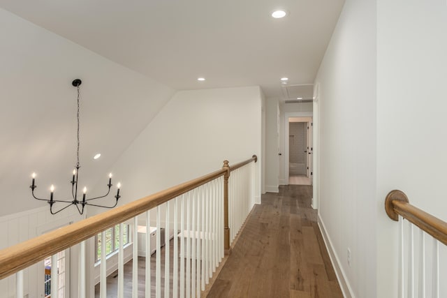 hall with vaulted ceiling, dark wood-type flooring, and a notable chandelier