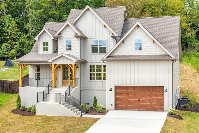 view of front of house featuring cooling unit, a porch, a garage, and a front lawn