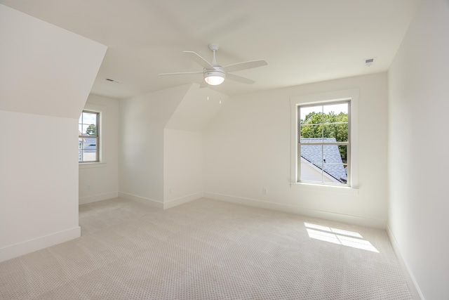 additional living space featuring light carpet, a wealth of natural light, and ceiling fan