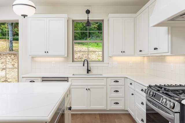 kitchen with white cabinets, stainless steel appliances, hanging light fixtures, and custom exhaust hood