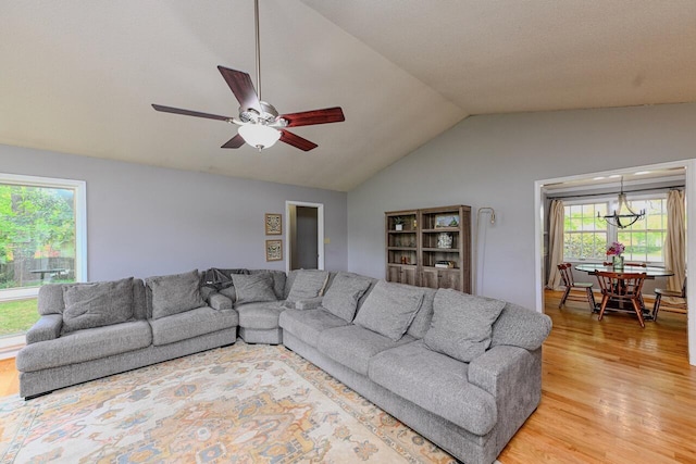 living room featuring light wood-style floors, ceiling fan with notable chandelier, and vaulted ceiling